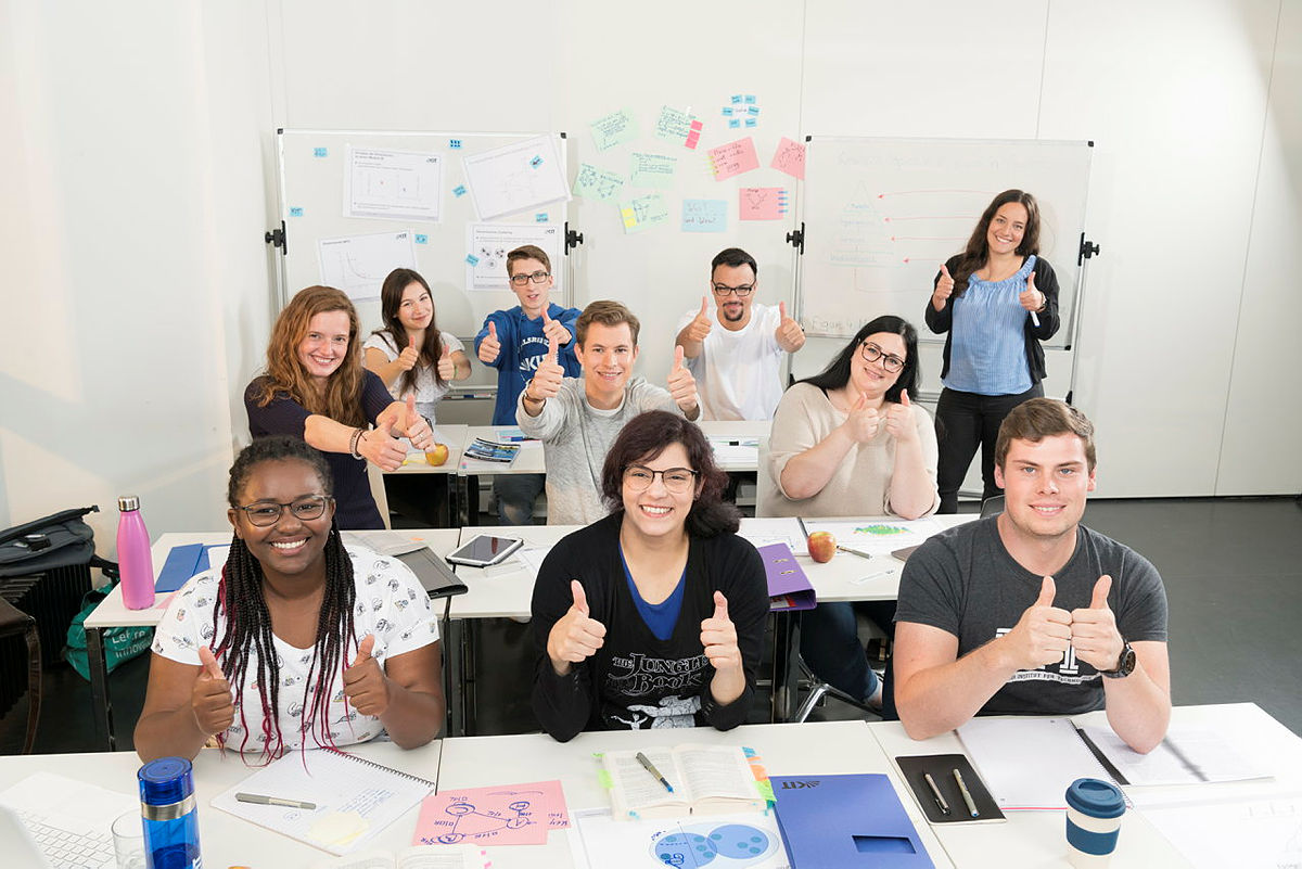 Studierende mit lachenden Gesichtern und Daumen-hoch-Gesten