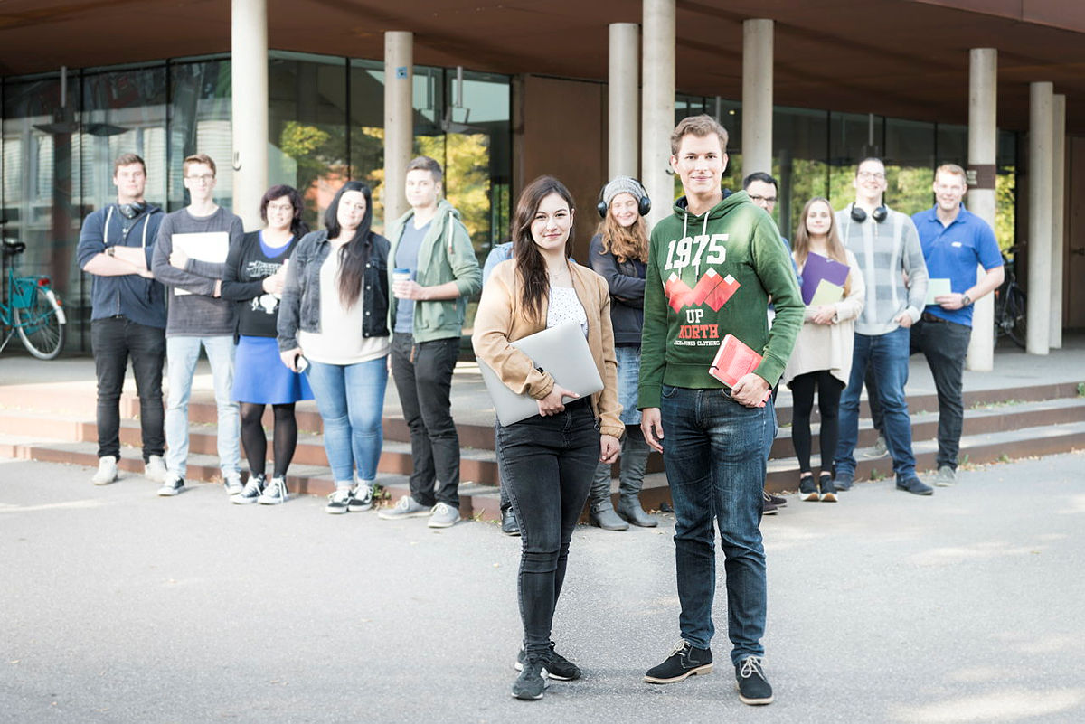 Studierende des KIT vor einem Gebäudeeingang auf dem Campus